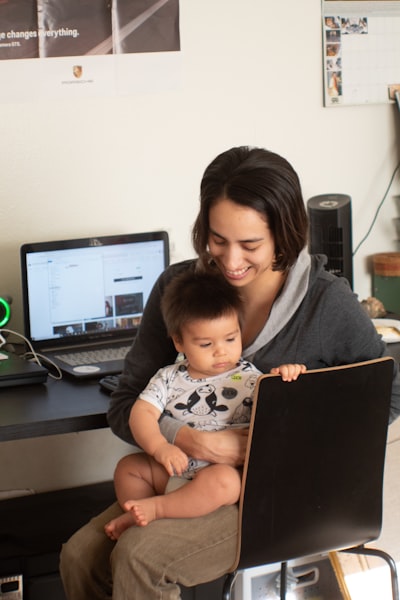 image qui illustre l'importance de l'équilibre vie pro et vie professionnelle avec une femme en train de travailler et un enfant sur les jambes